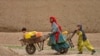 Afghan Kochi nomad girls push wheelbarrows as they fetch water along a street in Daman district of Kandahar province, Feb. 26, 2025.