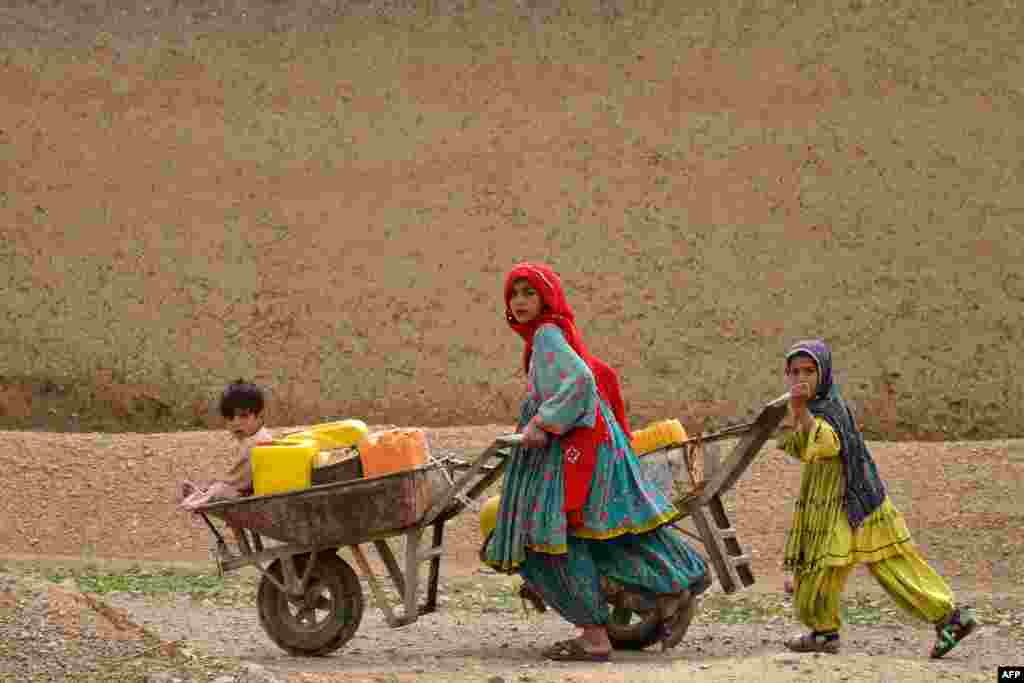 Afghan Kochi nomad girls push wheelbarrows as they fetch water along a street in Daman district of Kandahar province.