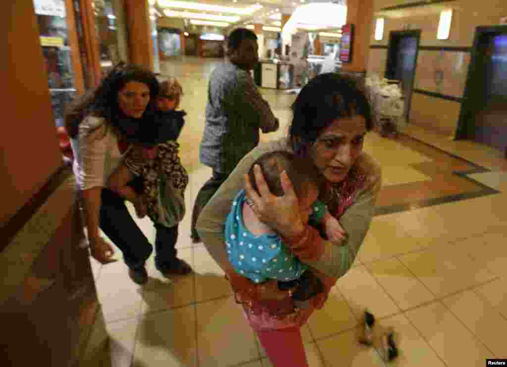 Para perempuan membawa anak-anaknya lari menyelamatkan diri saat polisi bersenjata memburu penembak yang menyerang Pusat Perbelanjaan Westgate di Nairobi, Kenya (21/9). (Reuters/Goran Tomasevic)