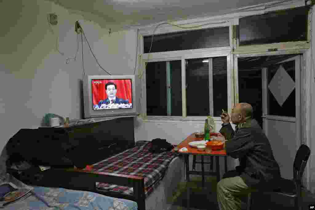 A Chinese man watches a news broadcast of Chinese President Hu Jintao speaking at the opening session of the 18th Communist Party Congress as he eats his dinner in his home in Beijing, November 8, 2012.