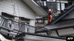 A local resident stands amid collapsed houses after a strong earthquake hit the area the night before, in Hakuba, some 300 kms northwest of Tokyo, Nagano prefecture, Nov. 23, 2014. 