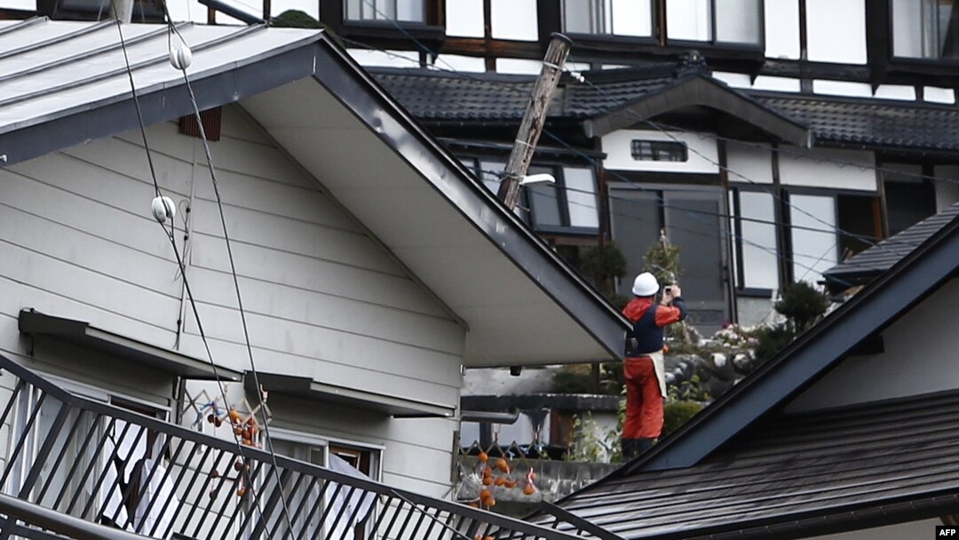 Seorang warga berdiri di tengah-tengah rumah-rumah yang rusak akibat gempa bumi yang mengguncang, di Hakuba, sekitar 300 km dari Tokyo, 23 November 2014. 