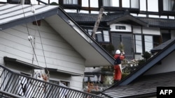 Seorang warga berdiri di tengah-tengah rumah-rumah yang rusak akibat gempa bumi yang mengguncang, di Hakuba, sekitar 300 km dari Tokyo, 23 November 2014. 