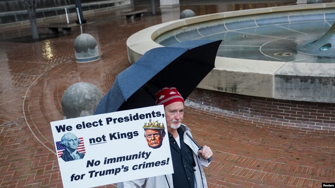 Una persona sostiene una pancarta, el día de una audiencia sobre el reclamo de inmunidad del ex presidente Donald Trump en el caso federal que lo acusa de intentar revertir su derrota electoral de 2020, en el Tribunal de Distrito de Columbia en Washington, el 9 de enero de 2024.