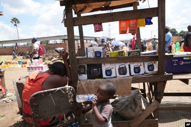 A woman sells small radio sets at a busy local marketplace stall in Harare on February 2, 2023. (AP Photo/Tsvangirayi Mukwazhi)