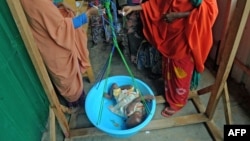 FILE - Newly displaced Somali women weigh their malnourished children as they try to receive medical treatment on the outskirts of Mogadishu, Somalia, on April 11, 2017. 