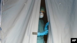 A medical staffer watches from a tent at one of the emergency structures that were set up to ease procedures at the Brescia hospital, northern Italy, March 12, 2020. 