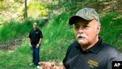 FILE - Dennis Parada, right, and his son Kem Parada stand at the site of the FBI's dig for Civil War-era gold in Dents Run, Pa., Sept. 20, 2018.