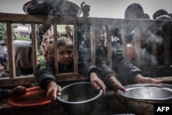 Anak-anak pengungsi Palestina berkumpul untuk menerima makanan di sebuah sekolah negeri di Rafah di Jalur Gaza selatan pada 19 Februari 2024. (Foto: AFP)