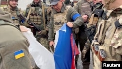 社交媒体视频截图显示哈尔科夫州科扎恰帕洛尼的镇长扎多仁科与一组军人撕毁一面俄罗斯旗。(2022年9月12日)