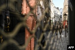 FILE - People walk near closed shops in Paris on March 20, 2021, on the first day of a new lockdown in France aimed to curb the spread of the COVID-19 cases.