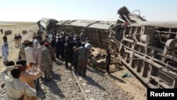 Para petugas, regu penolong dan warga setempat berkumpul di sekitar kereta penumpang yang anjlok akibat serangan bom di provinsi Baluchistan, Pakistan (21/10).