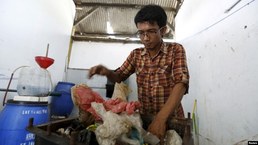 Hamidi menaruh limbah plastik ke dalam kotak besi sebelum membakar dan mengubahnya menjadi bahan bakar di TPA Rawa Kucing, Tangerang, Banten (17/3). (Reuters/Beawiharta)