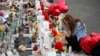 Gloria Garces kneels in front of crosses at a makeshift memorial near the scene of a mass shooting at a shopping complex, Aug. 6, 2019, in El Paso, Texas.