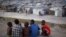 A group of boys sit on the rooftop of a home damaged by the 2010 earthquake, across from a camp where they now reside, Port-au-Prince, Haiti, January 9, 2013. 