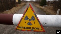 FILE - A sign reads "Radiation danger" in the village of Babchin, near the 30 km exclusion zone around the Chernobyl nuclear reactor, March 22, 2011.