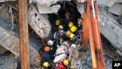 Emergency rescuers remove a body found in a collapsed building from an earthquake in Tainan, Taiwan, Feb. 7, 2016. 