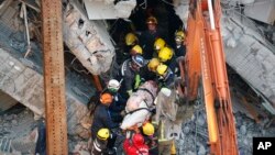 Emergency rescuers remove a body found in a collapsed building from an earthquake in Tainan, Taiwan, Feb. 7, 2016. 