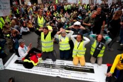 "Yellow vest" protesters kneel during an anti-government "yellow vests" (gilets jaunes) protest in Paris, Sept. 28, 2019.