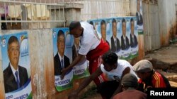 Para pendukung kandidat Presiden Madagaskar Robinson Jean-Louis menempelkan poster kampanye menjelang Pemilu di ibukota negara itu, Antananarivo (23/10).