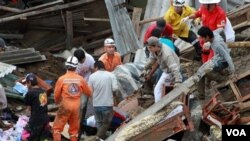 Tim penyelamat dan warga sekitar mengangkat korban dari longsoran tanah akibat hujan deras di Manizales, Kolombia (5/11).