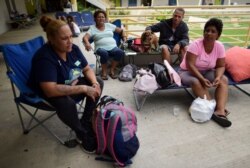 Residents, from left, Alma Torres Nazario, Olga Ramos, Danny Ramos and Elizabeth Ramos sit in an outdoor area of the Bernardino Cordero Bernard High School, amid aftershocks and no electricity in Ponce, Puerto Rico, Jan. 8, 2020.