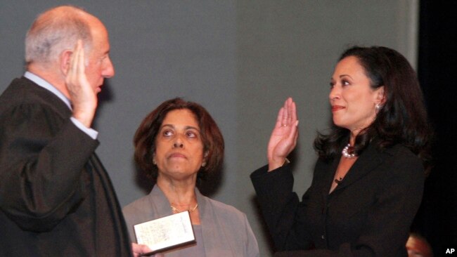 ARCHIVO - Kamala Harris con su madre, la Dra. Shyamala Gopalan, sosteniendo una copia de la Declaración de Derechos, recibe el juramento como fiscal de distrito del presidente de la Corte Suprema de California, Ronald M. George, el 8 de enero de 2004, en San Francisco.