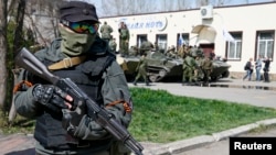 Un hombre armado, con listones negro y anaranjado de San Jorge, un símbolo asociado con los manifestantes prorrusos en Ucrania, monta guardia en Sloviansk.