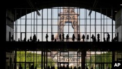 Visitors gather during a presentation visit of the "Grand Palais Ephemere," with the Eiffel Tower seen outside, in Paris, France, June 9, 2021.