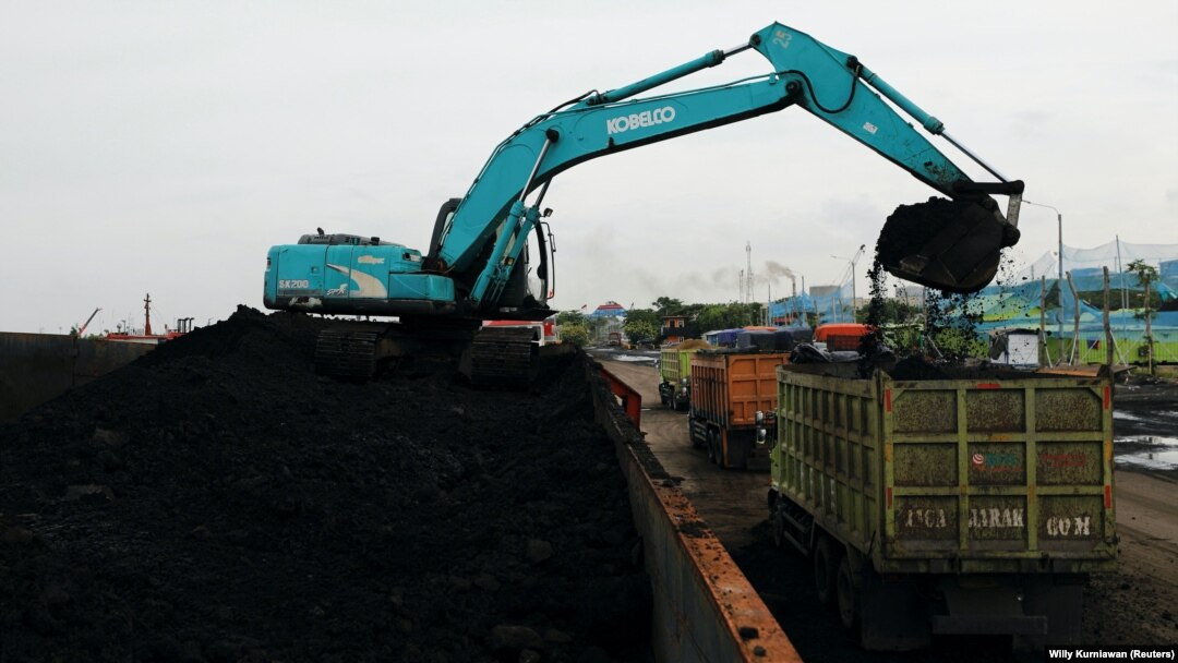 Sebuah alat berat terlihat mengeruk batu bara untuk dipindahkan ke dalam truk-truk pengangkut di Pelabuhan Karya Citra Nusantara di Jakarta Utara, pada 13 Januari 2022. (Foto: Reuters/Willy Kurniawan)