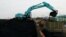 Sebuah alat berat terlihat mengeruk batu bara untuk dipindahkan ke dalam truk-truk pengangkut di Pelabuhan Karya Citra Nusantara di Jakarta Utara, pada 13 Januari 2022. (Foto: Reuters/Willy Kurniawan)
