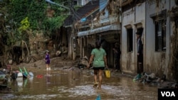 A woman walks down a flooded street in Mae Sai, Thailand, Sept. 22, 2024. (Tommy Walker/VOA)