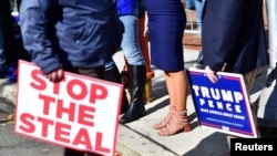 FILE - Trump supporters carry a "Stop the Steal" and campaign sign after Democratic presidential nominee Joe Biden overtook President Donald Trump in the Pennsylvania general election vote count, in Philadelphia, Nov. 6, 2020.