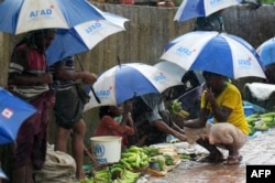 Rohingya refugees hide under umprellas during rainfall at Kutupalong refugee camp in Ukhia, Cox's Bazar, Bangladesh, Sept. 12, 2019.