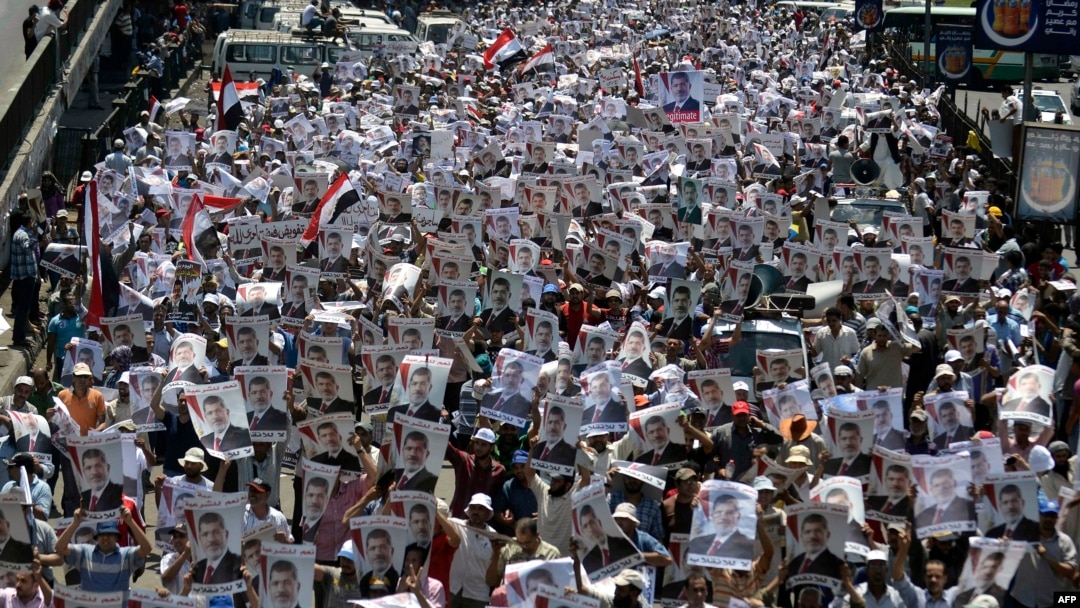Para pendukung presiden terguling Mohamed Morsi membawa potretnya dalam demo di luar masjid Rabaa al-Adawiya (26/7).