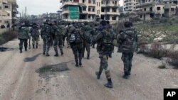 FILE - This Tuesday, Jan 12, 2016, file photo released by the Syrian official news agency SANA, shows Syrian government troops and allied militiamen walk inside the key town of Salma in Latakia province, Syria. 