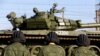 FILE - Russian tank crew members wait for their T-72B tank to be ready to move off a train shortly after Russian tanks arrived at a train station in the Crimean settlement of Gvardeiskoye.