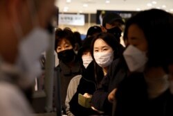 People wearing masks to prevent contracting the coronavirus wait in line to buy masks at a department store in Seoul, South Korea, Feb. 27, 2020.