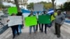 Un grupo de hondureños posan para la Voz de América frente al edificio de las Naciones Unidas en Nueva York con carteles de rechazo a la política de Xiomara Castro por cancelar el tratado de extradición con EEUU.