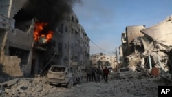 Syrian residents gather near destroyed buildings, after Syrian government forces hit Idlib city, Syria, Dec. 2, 2024. (Syrian Civil Defense White Helmets via AP)