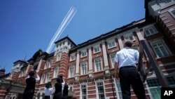 Pegawai stasiun melihat Impuls Biru Angkatan Udara Bela Diri Jepang yang terbang di atas Stasiun Tokyo sebagai dukungan mereka terhadap staf medis jepang dalam memerangi pandemi COVID-19, Jumat, 29 Mei 2020.