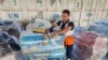 FILE - United Nations and Red Crescent workers prepare the aid for distribution to Palestinians at UNRWA warehouse in Deir Al-Balah, Gaza Strip, on Monday, Oct. 23, 2023.