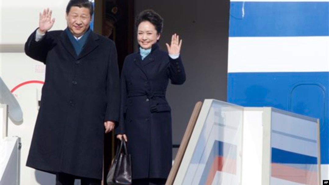 Presiden China Xi Jinping dan ibu negara Peng Liyuan saat tiba di bandar udara Vnukovo II, di luar kota Moskow. (AP/Ivan Sekretarev)