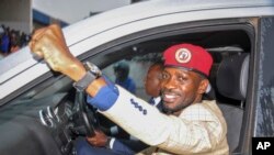 FILE - Ugandan presidential hopeful and political activist Bobi Wine, whose real name is Kyagulanyi Ssentamu, raises his fist in the air to gathered supporters as he leaves after meeting with the Electoral Commission, in Kampala, Uganda, Jan. 9, 2020.