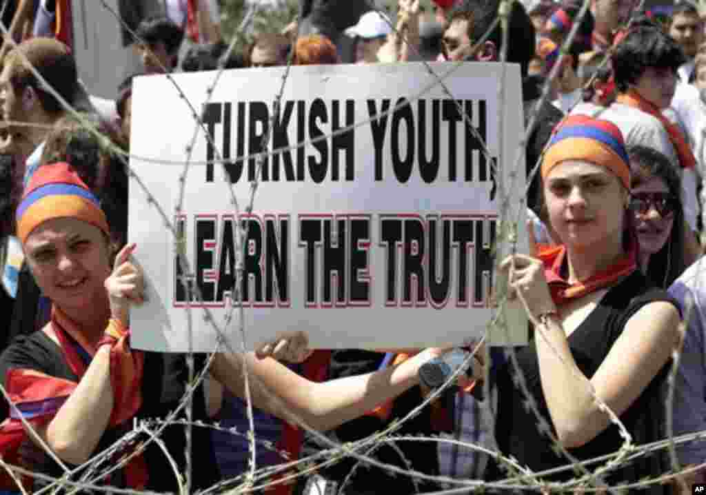 Lebanese Armenian protesters hold a placard as they cover their heads by Armenian flags, during a protest to mark the 97th anniversary of massacres in Turkey that began in April 1915 and in which hundreds of thousands of Armenians died, in front the Turki