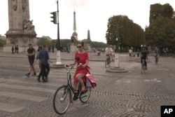 A woman rides on the Alexandre III bridge in Paris, Wednesday, Sept. 13, 2023. (AP Photo/John Leicester)