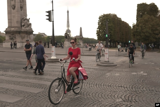 A woman rides on the Alexandre III bridge in Paris, Wednesday, Sept. 13, 2023. (AP Photo/John Leicester)