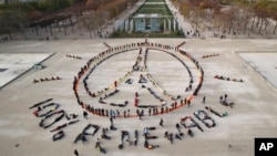 Environmentalist activists form a human chain representing the peace sign and the spelling out "100% renewable", on the side line of the COP21, United Nations Climate Change Conference near the Eiffel Tower in Paris, Sunday, Dec. 6, 2015. 