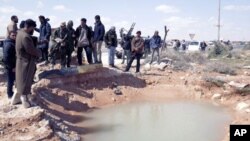 Anti-Gadhafi rebels survey the damage after an airstrike near the eastern city of Ras Lanuf, March 8, 2011