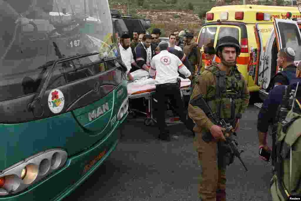An Israeli soldier stands guard as medics evacuate an injured girl from the scene where a Palestinian attacked civilians with a chemical substance near the settlement of Neve Daniel, Dec. 12, 2014. 
